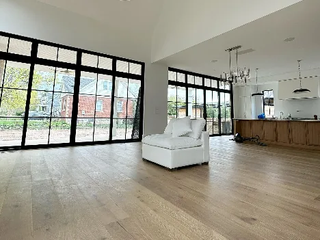 Open room with black window frames and wood floors
